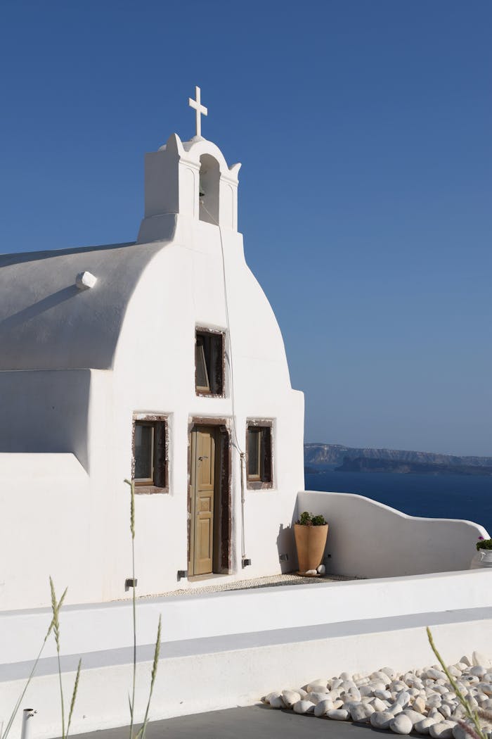 Explore the beauty of a traditional Greek church under a clear blue sky in Fira, Santorini.